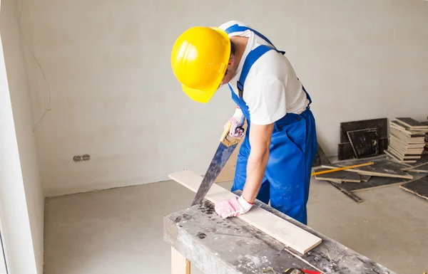 Close up of builder with arm saw sawing board — Zdjęcie stockowe