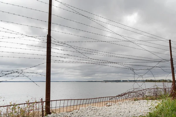 Cerca de alambre de púas sobre el cielo gris y el mar — Foto de Stock