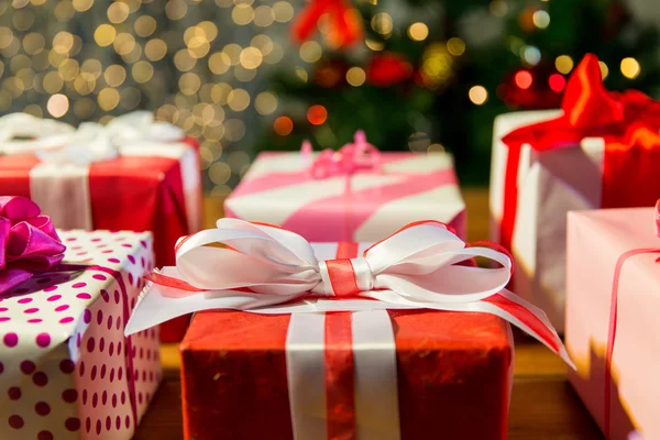 Close up of gift boxes over christmas tree lights — Stock Photo, Image