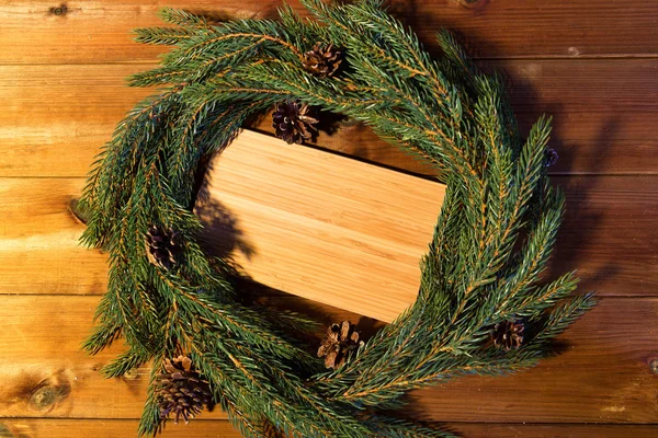 Natural green fir branch wreath and wooden board — Stock Photo, Image