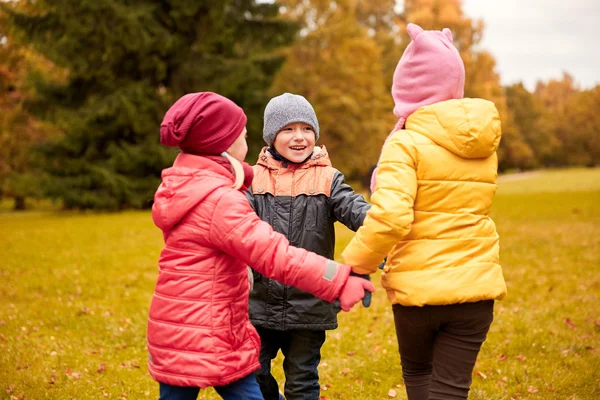 Kinderen hand in hand en spelen in de herfst park — Stockfoto