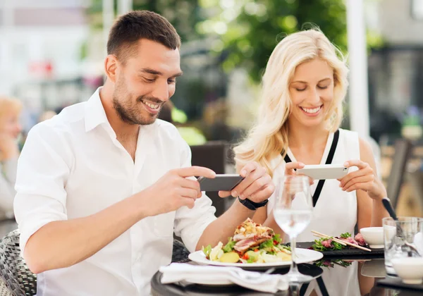 Glückliches Paar mit Smatphone, das Essen fotografiert — Stockfoto