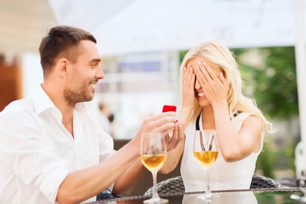 Šťastný pár se zásnubní prsten a víno v kavárně — Stock fotografie