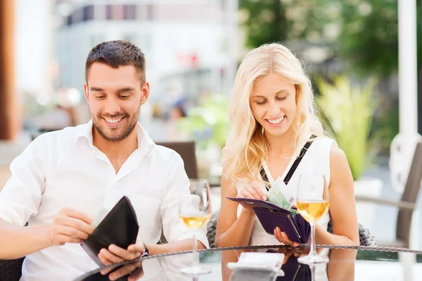 Feliz pareja con billetera pagando la factura en el restaurante — Foto de Stock