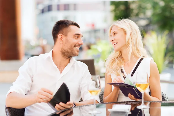 Счастливая пара с кошельком оплачивает счета в ресторане — стоковое фото