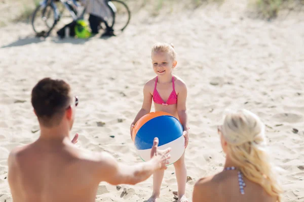 Familia feliz jugando con la bola inflable en la playa — Foto de Stock