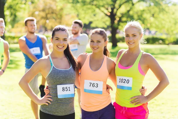 Felizes jovens mulheres desportivas com números de crachá de corrida — Fotografia de Stock