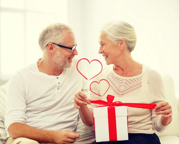 Happy senior couple with gift box at home — Stock Photo, Image