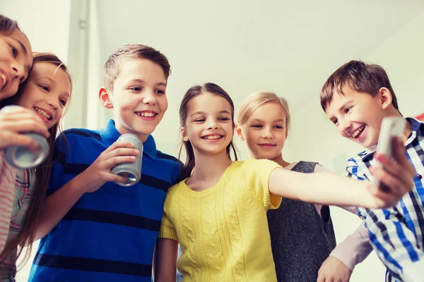 Grupo de niños de la escuela con teléfonos inteligentes y latas de refrescos —  Fotos de Stock