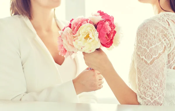 Close up of happy lesbian couple with flowers — Stock Photo, Image