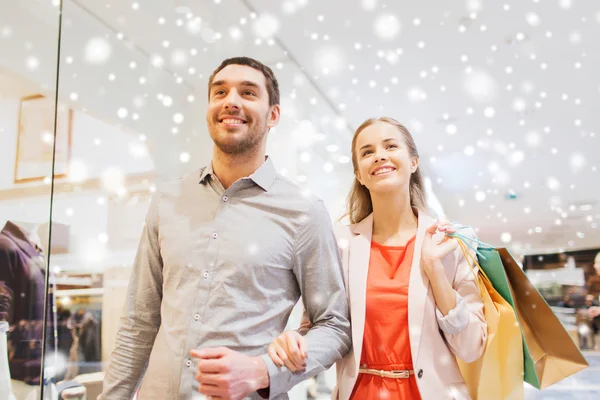 Lyckligt ungt par med shoppingväskor i köpcentret — Stockfoto