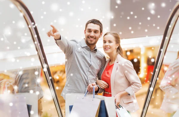 Pareja con bolsas de compras en escalera mecánica en el centro comercial —  Fotos de Stock