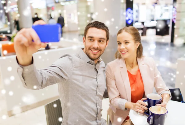 Happy couple with smartphone taking selfie in mall — Stock Photo, Image