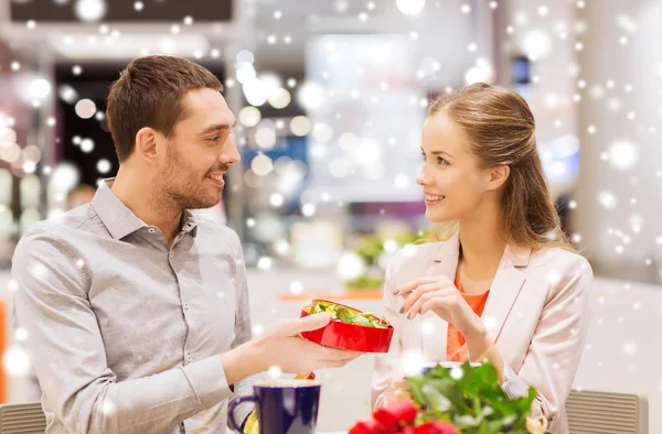 Glückliches Paar mit Geschenk und Blumen in Einkaufszentrum — Stockfoto