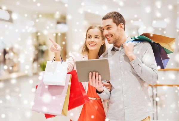 Pareja con tablet pc y bolsas de compras en el centro comercial —  Fotos de Stock