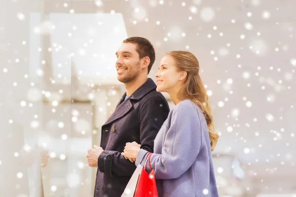 Feliz jovem casal com sacos de compras no shopping — Fotografia de Stock