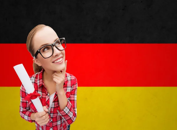Улыбающийся студент с дипломом над германским флагом — стоковое фото