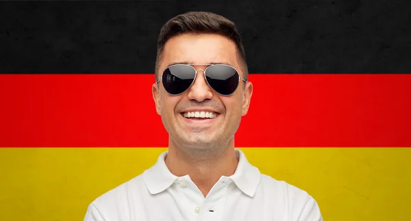 Лицо улыбающегося человека в солнечных очках над германским флагом — стоковое фото