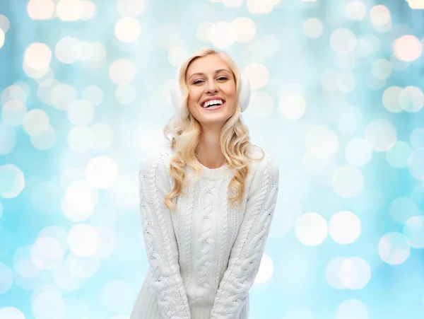 Lachende jonge vrouw in winter oorkappen en trui — Stockfoto