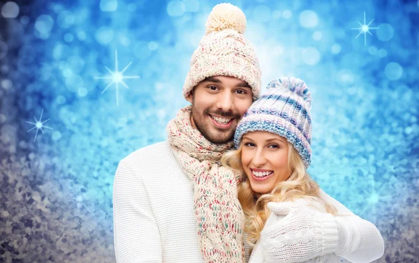 Happy couple in winter clothes hugging over lights — Stockfoto