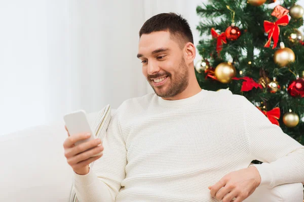 Smiling man with smartphone at home for christmas — Stock Photo, Image