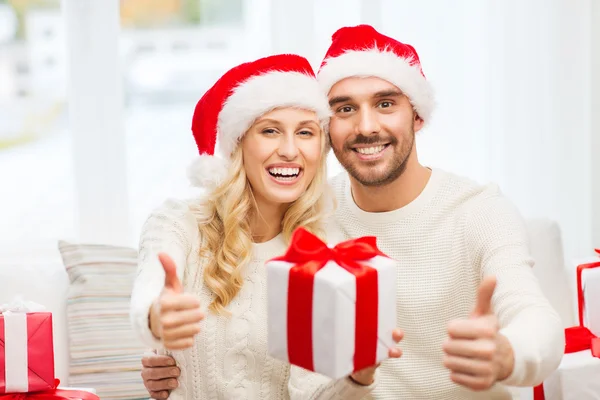 Casal feliz com presentes de Natal e polegares para cima — Fotografia de Stock