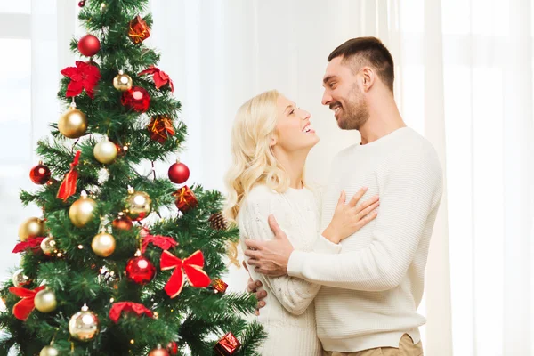 幸福的情侣拥抱在圣诞树在家附近 — 图库照片