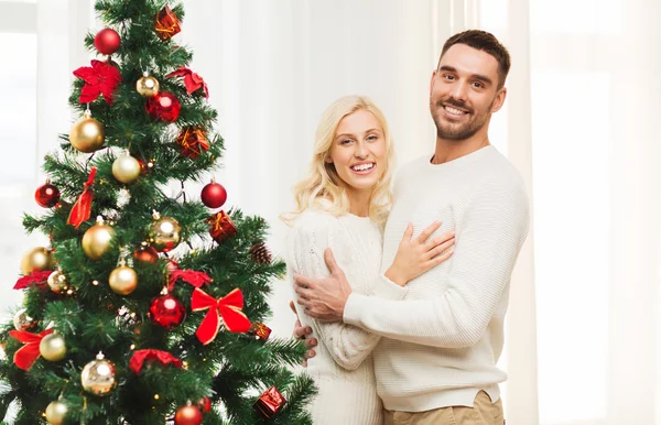 Felice coppia che abbraccia vicino albero di Natale a casa — Foto Stock