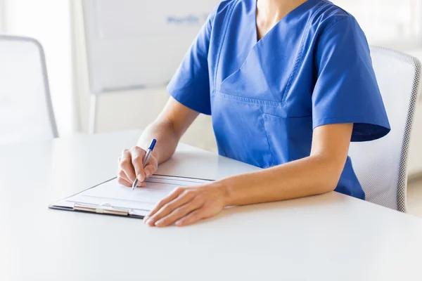 Close-up de médico ou enfermeiro escrevendo para área de transferência — Fotografia de Stock