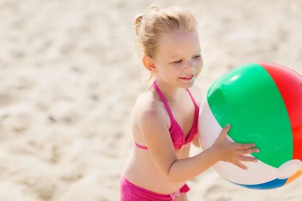 Niña feliz jugando pelota inflable en la playa — Foto de Stock