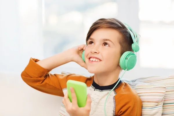 Glücklicher Junge mit Smartphone und Kopfhörer zu Hause — Stockfoto