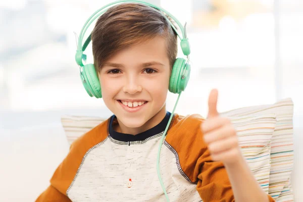 Lycklig pojke i hörlurar visar tummen upp hemma — Stockfoto