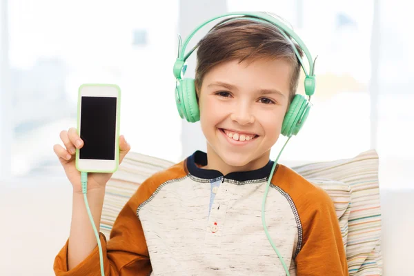 Glad pojke med smartphone och hörlurar hemma — Stockfoto