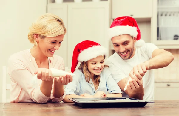 Familia feliz en sombreros de Santa Helper haciendo galletas — Foto de Stock