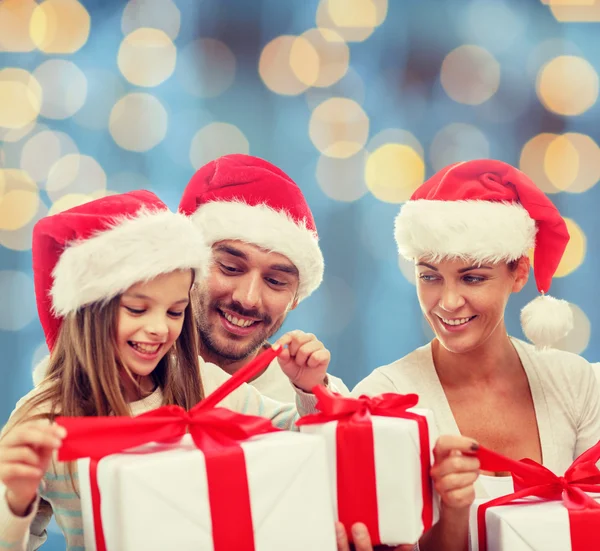 Glad familj i santa hattar sitter med presentförpackning — Stockfoto