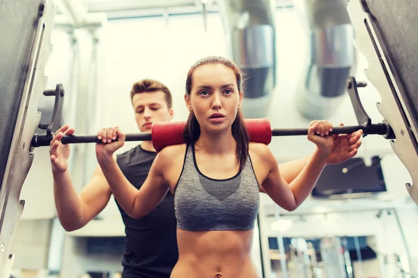 Homem e mulher com músculos de flexão barbell no ginásio — Fotografia de Stock