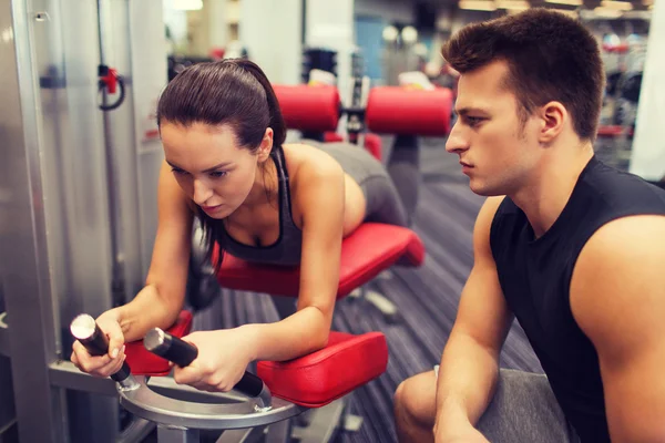 Jeune femme avec entraîneur exerçant sur la machine de gymnase — Photo