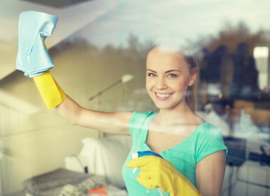 happy woman in gloves cleaning window with rag clipart