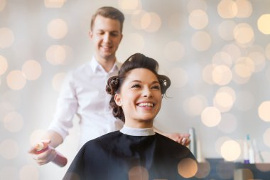 happy woman with stylist making hairdo at salon clipart