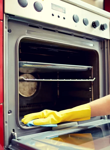 Закрытие женщины, моющей печь на домашней кухне — стоковое фото