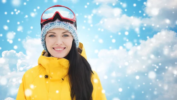 Gelukkig jonge vrouw in ski goggles over blauwe hemel — Stockfoto