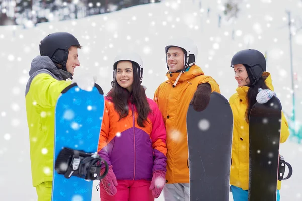 Amigos felizes em capacetes com snowboards falando — Fotografia de Stock
