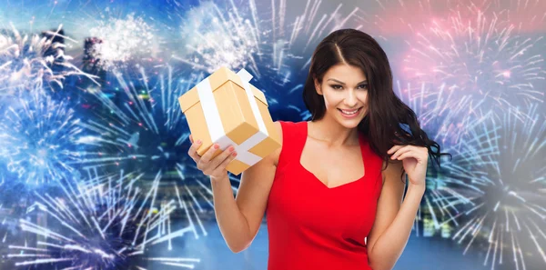 Glückliche Frau im roten Kleid mit Geschenk über Feuerwerk — Stockfoto