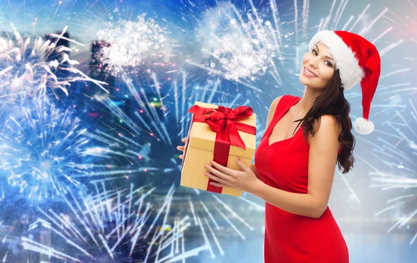 Donna felice in cappello di Babbo Natale con regalo sopra fuochi d'artificio — Foto Stock