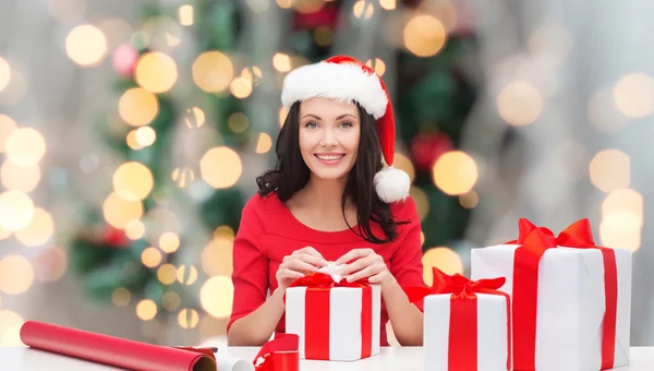 Smiling woman in santa helper hat packing gifts — Stock Photo, Image