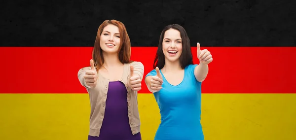 Sorrindo meninas mostrando polegares para cima sobre bandeira alemã — Fotografia de Stock
