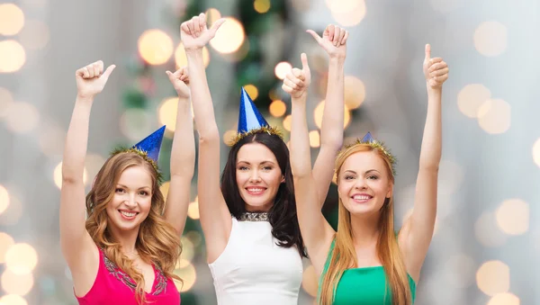 Sonrientes mujeres en gorras de fiesta mostrando los pulgares hacia arriba —  Fotos de Stock
