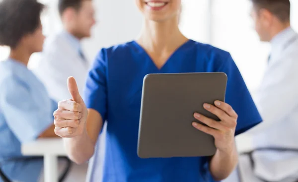 Close up of nurse with tablet pc showing thumbs — Stock Photo, Image