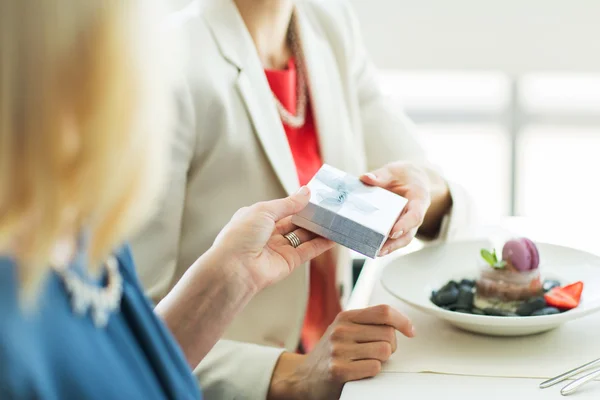 Close up of women giving present at restaurant — Stock Photo, Image