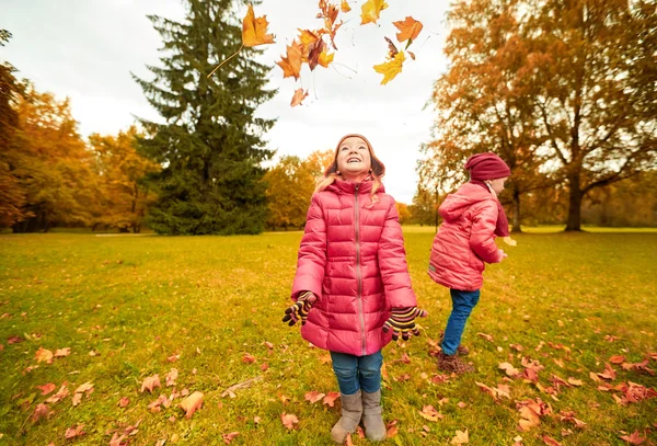 De gelukkige kinderen spelen met najaar bladeren in park — Stockfoto